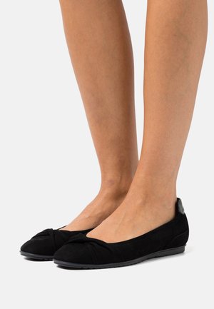 Sorte ruskind ballet flade sko med en knottet detalje ved tåen, en lav hæl og en kontrasterende tekstureret hældetalje. Glat overflade og fleksibelt design.