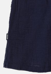 Tissu texturé bleu marine avec une surface froncée ; présente une petite étiquette noire étiquetée "SEASIDE" sur l'ourlet latéral.