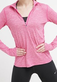 Rosa langärmliges Sportoberteil mit einem Halb-Reißverschluss-Design, das über eine melierte Textur und kontrastierende dunklere Akzente am Reißverschluss verfügt.