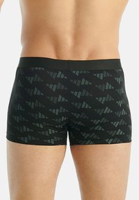 Svarta simbyxor med ett geometriskt mönster i mörkgrön. Tyget är glatt med en figursydd design och elastisk midja.