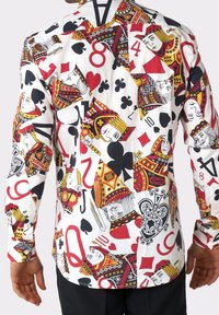 Chemise à manches longues en tissu blanc avec un motif vibrant de cartes à jouer en rouge, noir et jaune, comprenant divers symboles et figures de cartes.