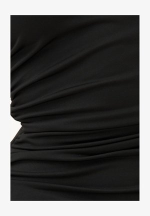 Gros plan d'un tissu noir avec un froncé horizontal créant une texture plissée sur une surface lisse.