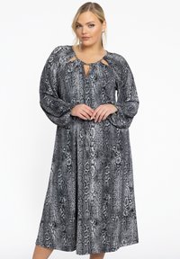 Robe longue à imprimé serpent noir et blanc avec des manches longues, un décolleté en trou de serrure et une coupe fluide et décontractée. Texture de tissu lisse.
