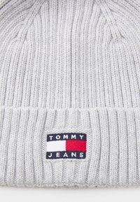 Grijze gebreide beanie met ribbelstructuur; beschikt over een rechthoekig logopatch in marineblauw, rood en wit met de tekst "TOMMY JEANS".