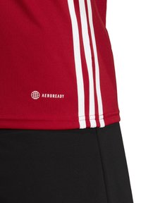 Rode sporttop met witte strepen aan de zijkanten, met een "AEROREADY" logo. Soepele stof, ontworpen voor vochtafvoer.