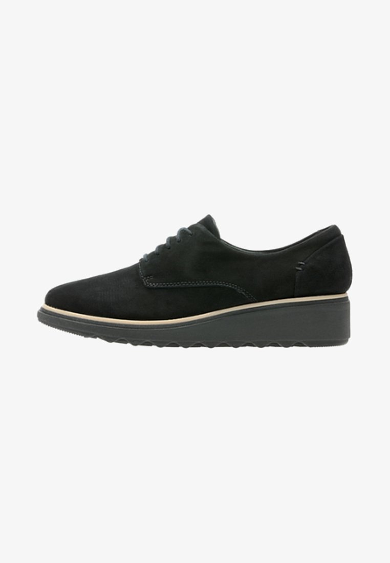 Chaussure à lacets en daim noir avec semelle compensée et garniture beige, conçue pour un usage décontracté ou formel.