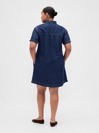 Robe chemise en denim, manches courtes, couleur bleu foncé, col, poches latérales, longueur mi-cuisse, coupe ample et ourlet cousu.