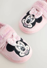 Pink plush slippers featuring an embroidered Minnie Mouse face, a fuzzy bow, and a soft texture for comfort. Adjustable strap closure.