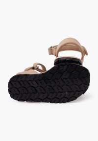 Sandalo beige con tomaia in pelle imbottita, doppie fibbie in Velcro e suola in gomma nera testurizzata con profonde scanalature per una migliore trazione.