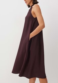 Ärmelloses, fließendes Kleid aus tiefrotburgunderfarbener Stoff mit seitlichen Taschen und lockerer Passform, mit rundem Ausschnitt und knielangem Saum.