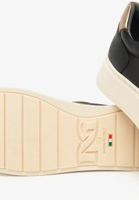 Sneaker noir avec semelle beige affichant le logo, taille 37, et le texte "Fabriqué en Italie" avec le drapeau italien sur la semelle.
