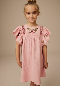 Helles rosafarbenes Kleid mit puffärmel, das über florale Stickereien am Oberteil und einen strukturierten Stoff verfügt, knieumspielend und mit lockerem Schnitt.