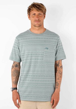 T-shirt à manches courtes bleu-vert clair avec une poche et un motif géométrique texturé. Fait en tissu doux, avec un col ras du cou.