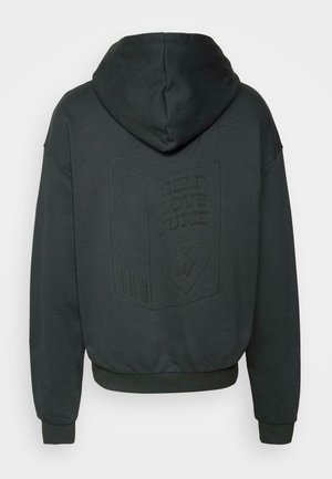 Ciemnoszara bluza z kapturem z dużym nadrukiem kartonu soku z napisem "SOK SAMOAKCEPTACJI" na plecach; posiada sznurek do regulacji kaptura oraz ściągacze przy mankietach.