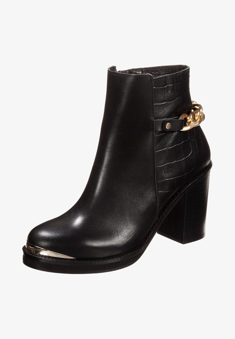 Svart läderankelboots med krokodilprägling, guldkedjedetalj, spetsig tå och kraftig hög klack. Metallisk tåkappa.