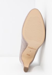 Beżowe buty Gabor z teksturowaną cholewką, szpiczastym czubkiem i gładką gumową podeszwą. Zawierają wytłoczone logo oraz elastyczne żebra na podeszwie.