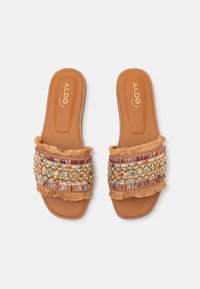 Sandales plates beige avec bandes en tissu multicolore perlées et bords frangés, de la marque ALDO, vues de dessus sur fond blanc.