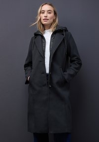 Zwarte jas met een getailleerd ontwerp, voorzien van een capuchon, knoopsluiting aan de voorkant en zijzakken. Het materiaal lijkt zacht met een gladde textuur.