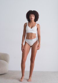 Witte katoenen lingerieset met een bralette en hoge taille slip; beide hebben een minimalistisch ontwerp met een contrasterende logoband.
