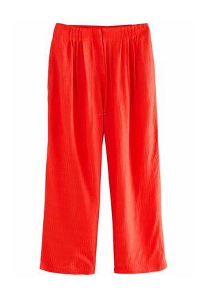 Pantalons rouges à jambe large en tissu texturé avec une coupe ample. Taille élastique avec plis pour un confort supplémentaire. Pas de matériel apparent ni de motifs.