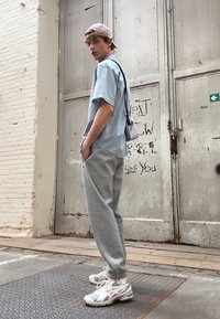 Világoskék, rövid ujjú ing texturált mintával, szürke sportnadrág, fehér sneaker pastel árnyalatokkal, és bézs baseball sapka.