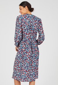 Abito floreale blu scuro con motivi rossi, rosa e turchesi. Maniche lunghe, cintura in vita e orlo a ginocchio. Tessuto leggero con una texture fluida.