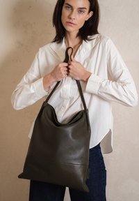 Strakke donkergrijze leren tote bag met een gestructureerd oppervlak, met een slouchy ontwerp en twee stevige handvatten om te dragen.