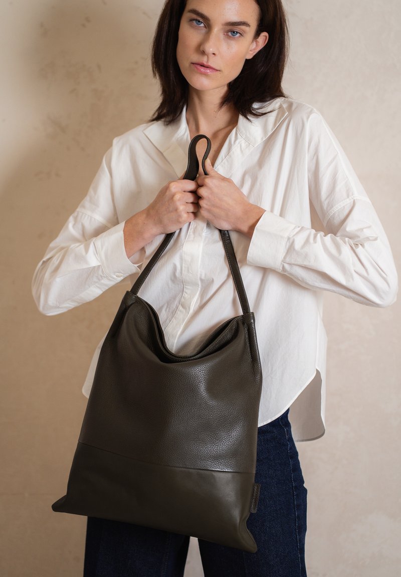 Strakke donkergrijze leren tote bag met een gestructureerd oppervlak, met een slouchy ontwerp en twee stevige handvatten om te dragen.