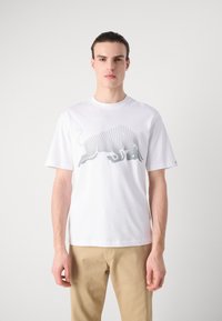 Hvit bomulls T-skjorte med et gråprikket oksedesign på fronten, korte ermer og rund hals. Glatt tekstur og avslappet passform.