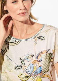 Zachte stoffen blouse met een bloemenpatroon in verschillende kleuren, met een ronde halslijn geaccentueerd door een blauw-witte rand.