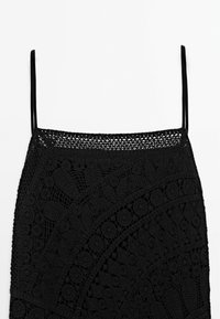 Schwarzes gehäkeltes Kleid mit dünnen Schulterträgern. Komplexe Musterstruktur mit floralen und geometrischen Designs. Figurbetonte Silhouette.