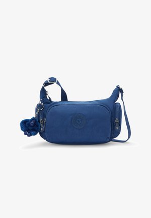 Blue nylon shoulder bag with a rounded shape, front zipper pocket, logo patch, and a furry monkey keychain accent. Adjustable strap included.