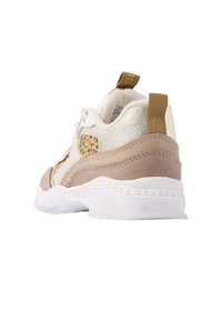 Sneaker met een witte rubberen zool, beige suede en gouden metallic accenten, met een gepatternd stoffen paneel en een trekband op de hiel.