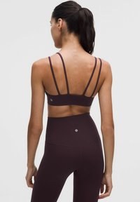 Bordowy stanik sportowy z cienkimi, wieloma ramiączkami oraz dopasowanymi, wysokimi legginsami, wykonany z gładkiego, elastycznego materiału, z detalem logo.