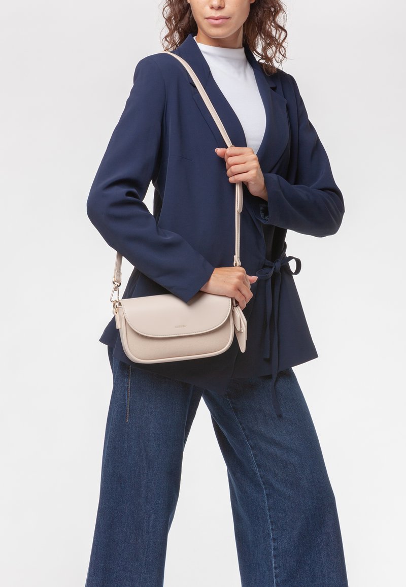 Borsa a tracolla beige con finitura in pelle liscia, pattina curva e tracolla regolabile, esposta su uno sfondo neutro.