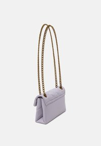 Malá levandulová prošívaná kabelka s klopou, která má zlatý řetízkový popruh. Kabelka má obdélníkový tvar a hladký povrch.