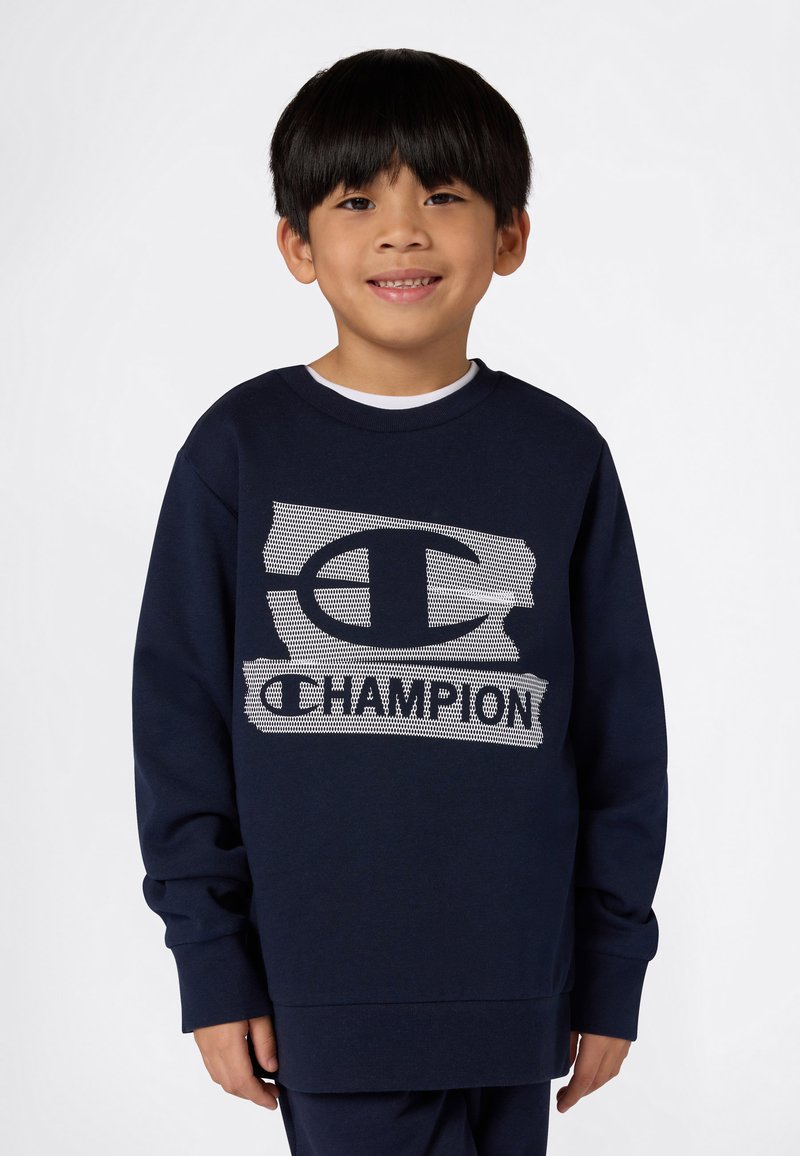 Mørkeblå sweatshirt med et stort hvitt mesh-stil "C"-logo og "CHAMPION" tekst. Laget av et mykt stoff med en avslappet passform og rund hals.