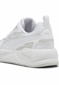 Baskets sportives blanches en maille texturée au design élégant, avec une semelle épaisse, des accents gris subtils et un logo de marque sur le talon.