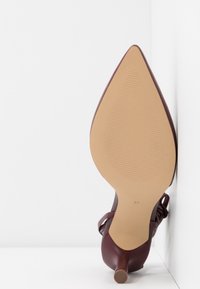 Scarpa con tacco alto color bordeaux, con punta affusolata e tacco sottile e affusolato. Parte superiore in pelle liscia e suola beige testurizzata. Taglia 37 stampata sulla suola.