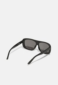 Black sunglasses with rectangular frames, dark tinted lenses, and shiny plastic arms featuring subtle branding on the inner side.