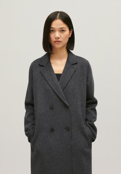 Manteau en laine gris foncé avec un design à double boutonnage, des revers crantés, des poches latérales et des boutons noirs. Texture lisse avec une coupe ajustée.