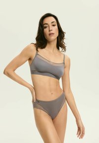 Graue Bralette mit Mesh-Akzenten und verstellbaren Trägern, kombiniert mit passenden hochgeschnittenen Slips, die eine glatte Textur und minimale Details aufweisen.