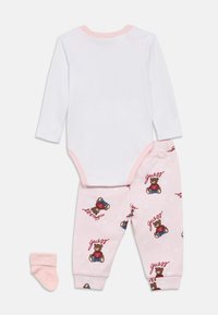 Βρεφικό βαμβακερό σετ με λευκό κορμάκι μακρυμάνικο και ροζ πυτζάμες με σχέδιο αρκούδας και τη λέξη "guess". Περιλαμβάνει ροζ κάλτσες.