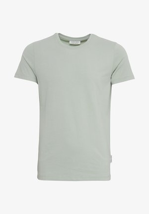 Svetlo zelena kratka majica s kratkimi rokavi, narejena iz mehkega blaga, z okroglim izrezom, naravnim robom in majhno etiketo na strani.