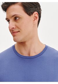 Niebieski t-shirt z okr�ągłym dekoltem wykonany z miękkiego materiału. Posiada gładką fakturę i dobrze dopasowany fason, co zapewnia komfort i wszechstronność.