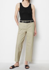 Zwarte geribbelde tanktop, lichtbeige hoge taillebroek, zwarte riem en zwarte slipper sandals. Casual, getailleerde pasvorm met zakken.