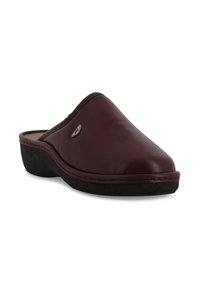 Zoccoli slip-on in pelle bordeaux con punta arrotondata, soletta imbottita e suola in gomma nera testurizzata. Presenta un piccolo accento metallico con il logo.