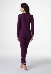 Set di pigiami viola a costine con maniche lunghe e polsini elasticizzati, con dettagli in pizzo sulle maniche e sui orli dei pantaloni. Tessuto morbido.