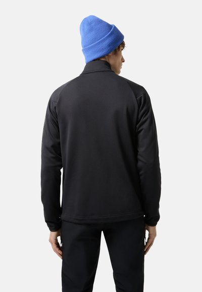 Black, long-sleeved jacket with a smooth texture and raglan sleeves, paired with a blue knit beanie, viewed from the back.