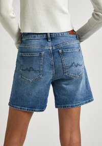 Bermudas de mezclilla en azul claro con un acabado ligeramente desgastado, que presentan dos bolsillos traseros con costuras en zigzag y una cintura de altura media.